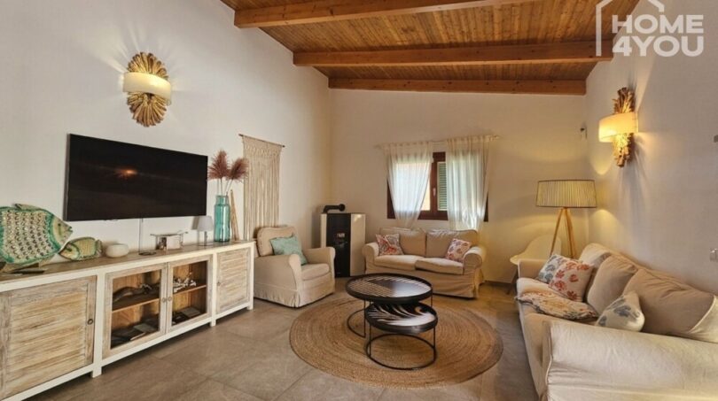Bright living room with wooden beam ceiling, sofa group, TV cabinet and Mediterranean decoration in bungalow Alcúdia.