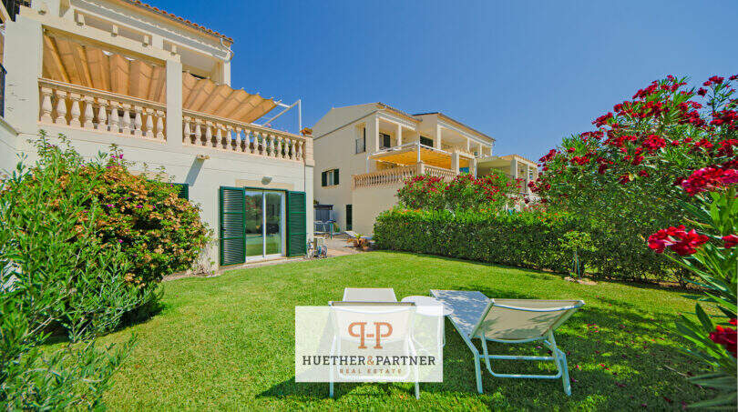 Gepflegter Garten mit Liegestühlen, Balkon mit Markise und blühenden Sträuchern des Reiheneckhauses in Porto Cristo Novo.