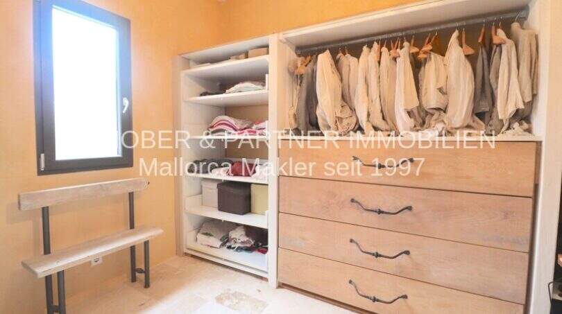 Begehbarer Kleiderschrank mit Hängestange, Holzkommode und Regalflächen im sanierten Landhaus Port de Manacor