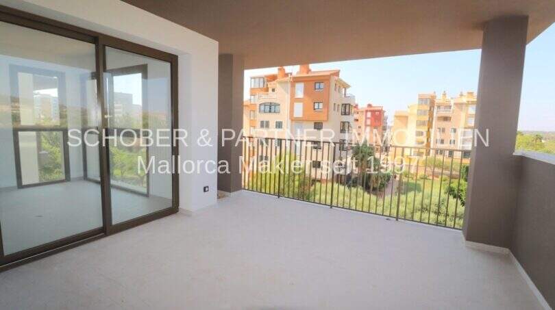 Geräumige Terrasse mit Glasschiebtür und Blick auf Apartmentanlage in Cala Millor, heller Fliesenboden