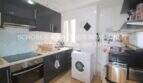 Cocina con frentes de alto brillo oscuro, horno empotrado, placa vitrocerámica y lavadora en apartamento Porto Cristo