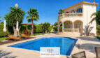 Villa Sa Torre Llucmajor: Mediterrane Außenansicht mit Pool, Palmen, Terrasse und elegantem Balkon bei blauem Himmel.