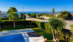 Außenbereich der Villa in Sa Torre mit Pool, gepflegtem Garten, Palmen und Meerblick auf Mallorca.