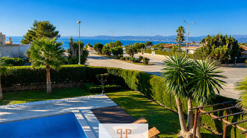 Außenbereich der Villa in Sa Torre mit Pool, gepflegtem Garten, Palmen und Meerblick auf Mallorca.