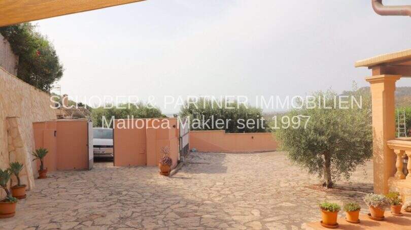 Paved courtyard with olive tree, view of garage and panoramic landscape in Son Servera