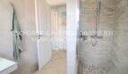 Modern bathroom with natural stone shower, glass partition and towel hooks in Villa Son Servera with sea view.