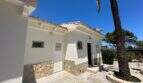 Außenbereich der mediterranen Villa in Cala Murada mit weißer Fassade, Natursteinverkleidung und Palme.