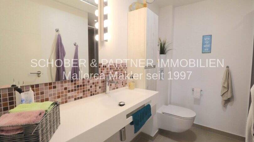 Modernes Badezimmer mit großem Waschtisch, Mosaik-Fliesenspiegel und WC in Garten-Eck-Wohnung Sa Coma