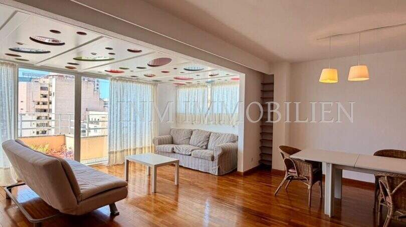 Helles Wohnzimmer der Dachgeschosswohnung Blanquerna mit Parkettboden, Balkon und bunter Deckengestaltung