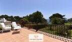 Sonnige Terrasse der Erdgeschosswohnung in Cala Mandia mit Meerblick, Rattanmöbeln und üppigem Garten.