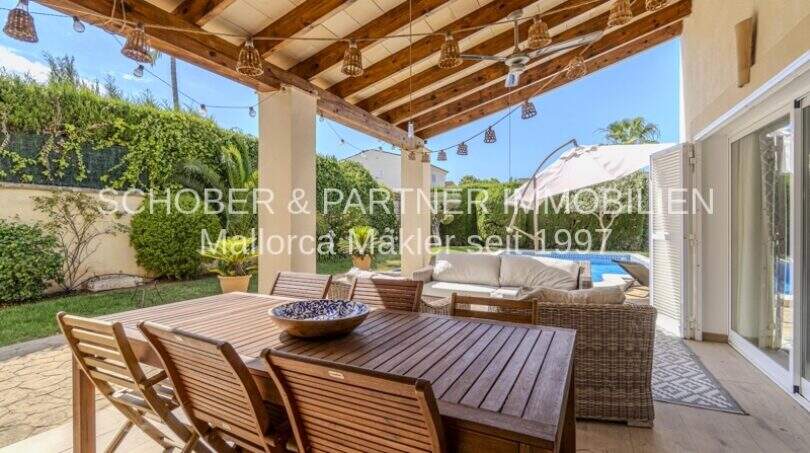Überdachte Terrasse mit Holzbalken, Esstisch, Loungebereich und Poolblick der mediterranen Villa in Sa Coma