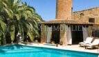 Pool mit Sonnenliegen, Palmen und historischem Steinturm einer rustikalen Finca in S'Aranjassa, Palma