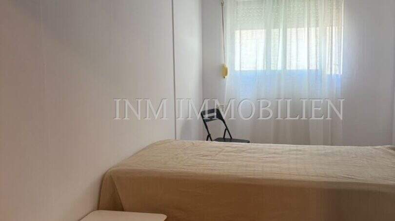 Helles Schlafzimmer mit Doppelbett, Holzparkett und Fenster mit Vorhängen in Dachgeschosswohnung Palma Blanquerna