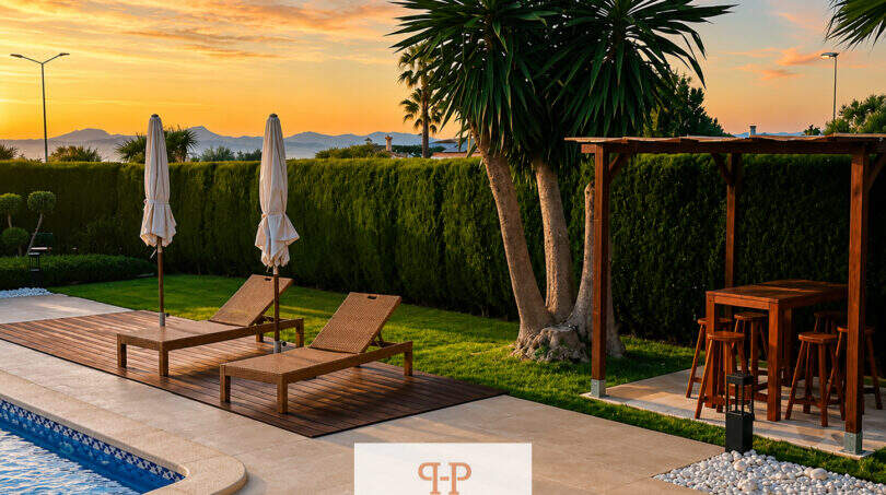 Poolbereich der Villa Sa Torre mit Sonnenliegen, Pergola und Palmen bei Sonnenuntergang mit Meerblick