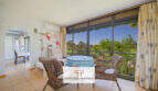 Heller Wohnbereich mit Korbmöbeln, Panoramafenster und Gartenblick in Apartment Cales de Mallorca