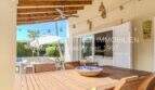 Überdachte Terrasse mit Holztisch, Deckenventilator und Blick auf den Gartenbereich der mediterranen Villa in Sa Coma.