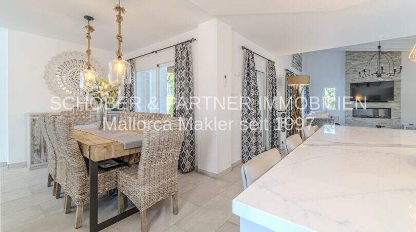 Eleganter Essbereich mit Rattanstühlen, Marmortresen und Kamin in mediterraner Villa Sa Coma