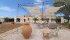 Sonnige Terrasse mit Sonnensegeln, Lounge-Möbeln und Terrakotta-Vase beim Landhaus in Portocristo