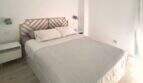 Helles Schlafzimmer im Penthouse Portitxol mit Doppelbett, Holzkopfteil und weißen Wänden