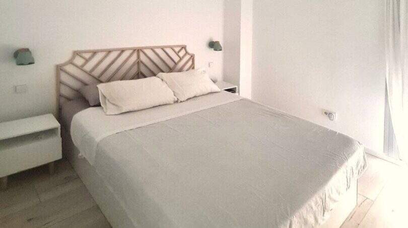 Helles Schlafzimmer im Penthouse Portitxol mit Doppelbett, Holzkopfteil und weißen Wänden