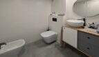 Modernes Badezimmer des Penthouses in Portitxol mit Bidet, Wand-WC, Waschtisch und ovalem Spiegel.