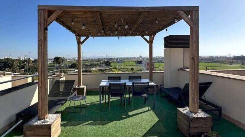 Dachterrasse des Penthouses mit Holzpergola, Essbereich, Kunstrasenboden und Panoramablick über Palma de Mallorca.