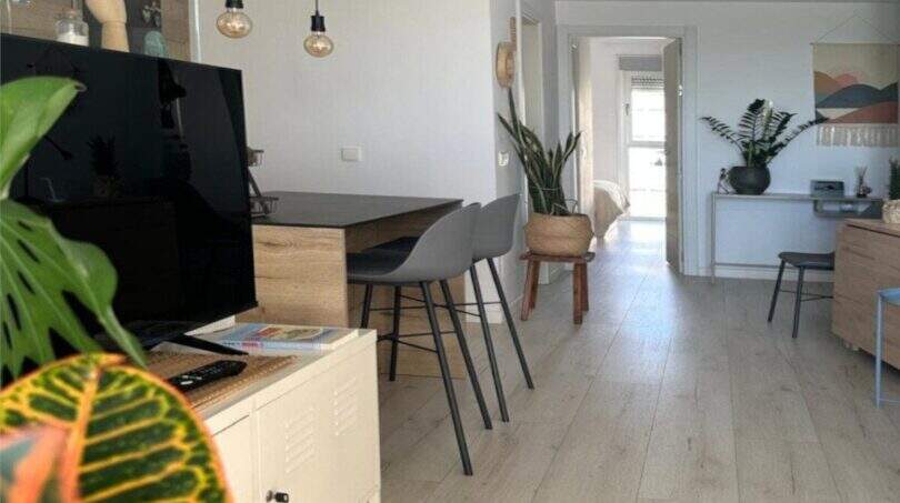 Helles Wohnzimmer mit Holzboden, Hängeleuchten, TV-Möbel und Zimmerpflanzen im Penthouse Portitxol