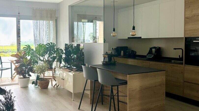 Offene Küche mit Holzinsel, Pendelleuchten und Pflanzen im Penthouse Portitxol, Palma de Mallorca