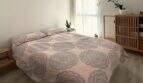 Helles Schlafzimmer mit Doppelbett, Mandala-Bettwäsche, Holzboden und Naturpflanzen im Penthouse Portitxol
