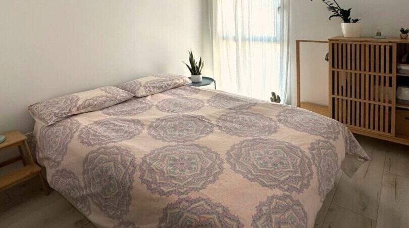 Helles Schlafzimmer mit Doppelbett, Mandala-Bettwäsche, Holzboden und Naturpflanzen im Penthouse Portitxol