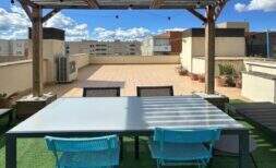 Dachterrasse des Penthouses in Portitxol mit Pergola, Lichterketten, türkisen Stühlen und Blick über Palma de Mallorca.