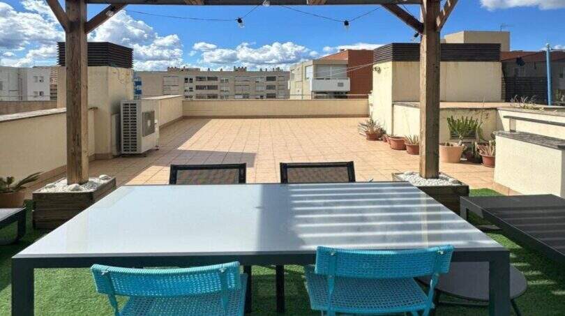 Dachterrasse des Penthouses in Portitxol mit Pergola, Lichterketten, türkisen Stühlen und Blick über Palma de Mallorca.