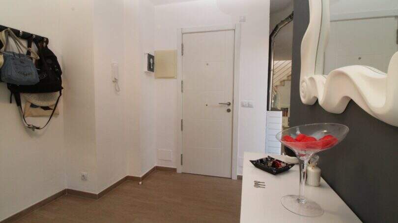 Heller Eingangsbereich der Penthouse-Maisonette in Palma mit weißer Tür, Garderobe und elegantem Dekospiegel.