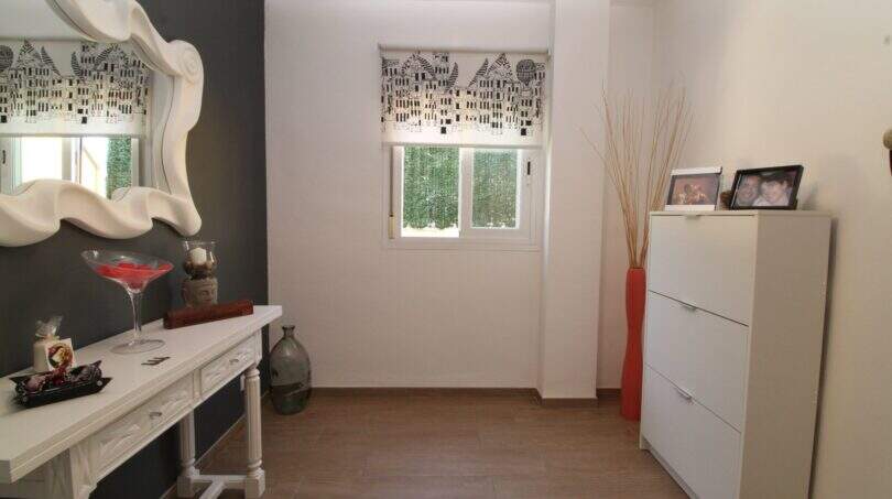 Heller Eingangsbereich der Maisonette mit weißem Konsolentisch, elegantem Spiegel und modernem Schuhschrank