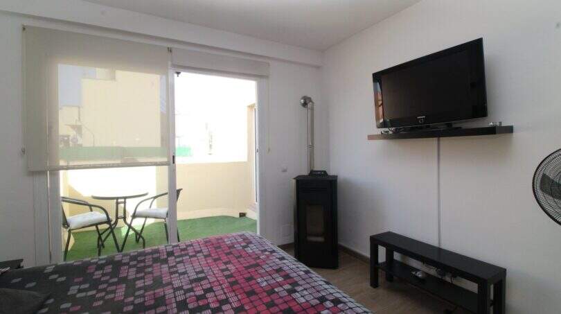 Helles Schlafzimmer mit Doppelbett, Wandmontiertem TV und Zugang zur Terrasse mit Sitzbereich im Penthouse Palma