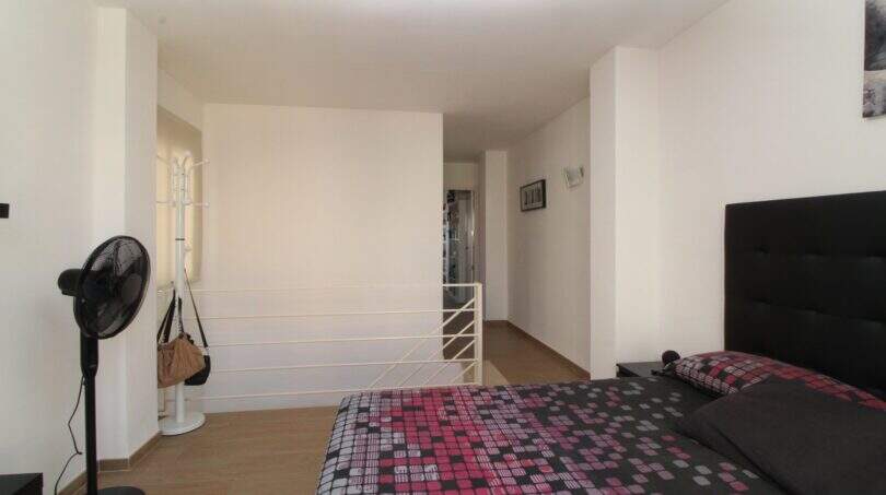 Helles Schlafzimmer der Penthouse-Maisonette mit Doppelbett, schwarzem Kopfteil und Galeriebereich mit Treppenaufgang.