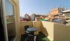 Sonniger Balkon mit Rattanmöbeln und Stadtblick über die Dächer von Palma de Mallorca
