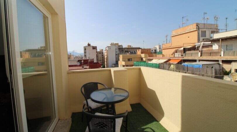 Sonniger Balkon mit Rattanmöbeln und Stadtblick über die Dächer von Palma de Mallorca