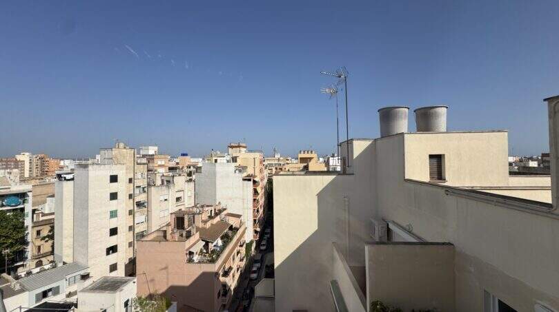 Panoramablick vom Dachterrasse der Penthouse-Maisonette über die Stadtdächer von Palma de Mallorca bei blauem Himmel.