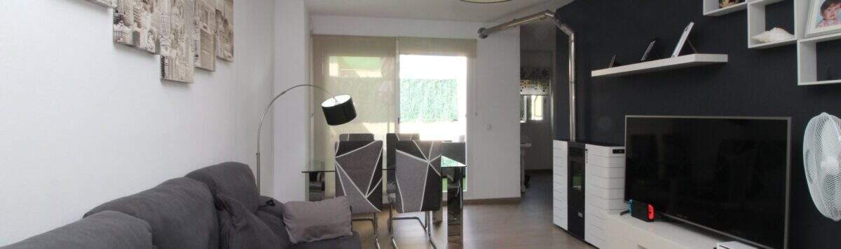 Helles Wohnzimmer der Penthouse-Maisonette in Palma mit grauem Sofa, modernem TV-Bereich und Zugang zur Terrasse.