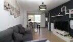 Helles Wohnzimmer der Penthouse-Maisonette in Palma mit grauem Sofa, modernem TV-Bereich und Zugang zur Terrasse.