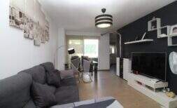 Helles Wohnzimmer der Penthouse-Maisonette in Palma mit grauem Sofa, modernem TV-Bereich und Zugang zur Terrasse.
