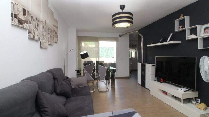 Helles Wohnzimmer der Penthouse-Maisonette in Palma mit grauem Sofa, modernem TV-Bereich und Zugang zur Terrasse.