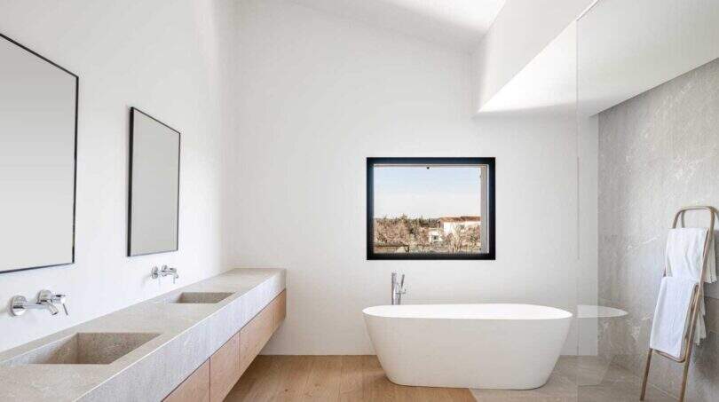 Modernes Badezimmer mit freistehender Wanne, Doppelwaschbecken und Holzboden in Anwesen Marratxí