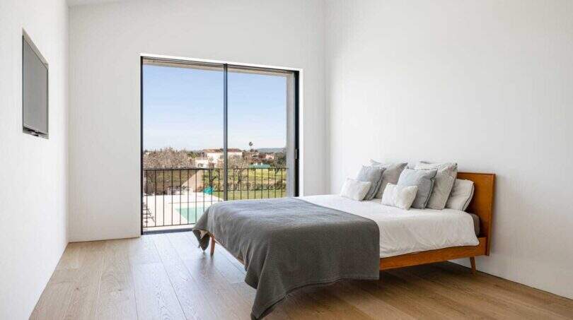 Helles Schlafzimmer mit Holzboden, Doppelbett und Balkon mit Pool- und Gartenblick in Marratxí