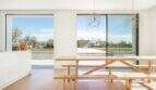 Heller Essbereich mit Holztisch, Designerlampen und Panoramafenstern mit Blick auf Pool und Garten in Marratxí.