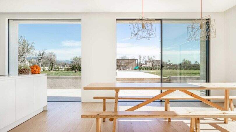 Heller Essbereich mit Holztisch, Designerlampen und Panoramafenstern mit Blick auf Pool und Garten in Marratxí.