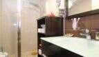 Modern bathroom of the ground floor apartment in Palma with glass shower, dark sink and wall mirror.