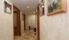 Bright hallway of the ground floor apartment in Palma with marble floor, wooden doors and family photos on the wall.