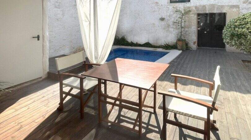 Terraza de madera con muebles de jardín y pequeña piscina en el patio interior de la casa de pueblo en Sencelles.
